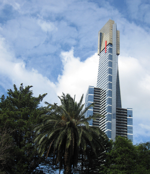 mid-ground complexly-shaped tower; foreground trees (palm in center); background: sky